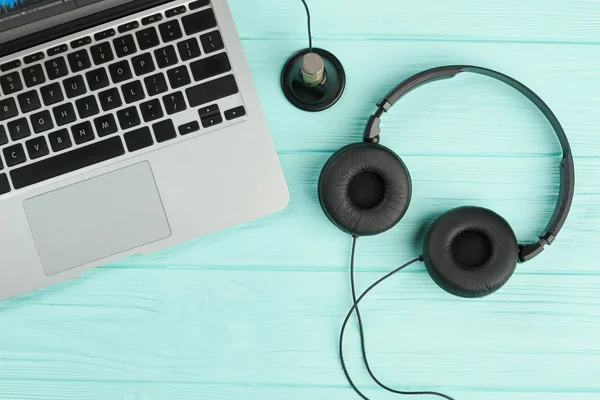 Laptop e fones de ouvido no fundo azul . — Fotografia de Stock