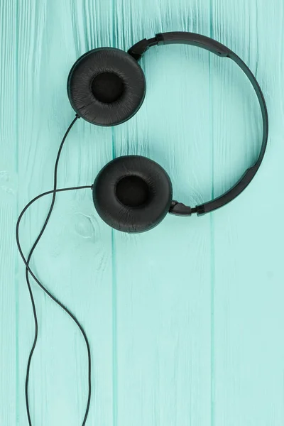 Black headphones on blue wooden background.