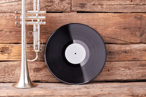 Trumpet and vinyl record on old wood. — Stock Photo, Image