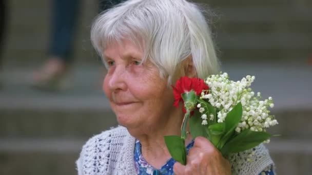 Portrét starého starší babička s květinami. — Stock video