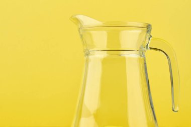 Sarı zemin üzerine temiz cam sürahi.