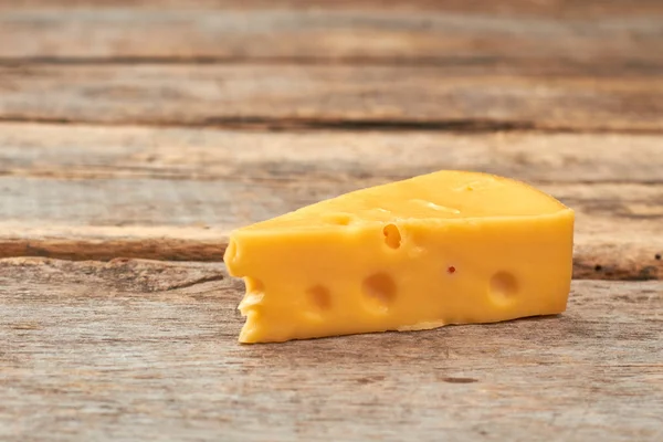 Piece of swiss cheese on wooden background. — Stock Photo, Image