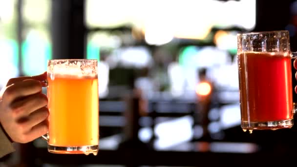 Dos hombres sosteniendo vasos de cerveza y tintineo . — Vídeo de stock