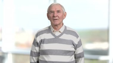 Tahriş olmuş yaşlı bir adam, arka plan bulanık.