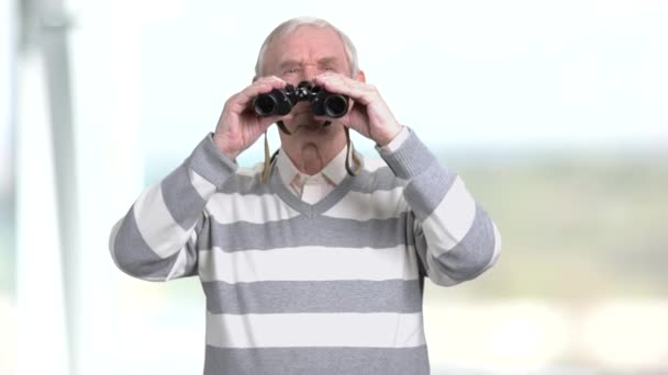 Älterer Mann mit Fernglas, verschwommener Hintergrund. — Stockvideo