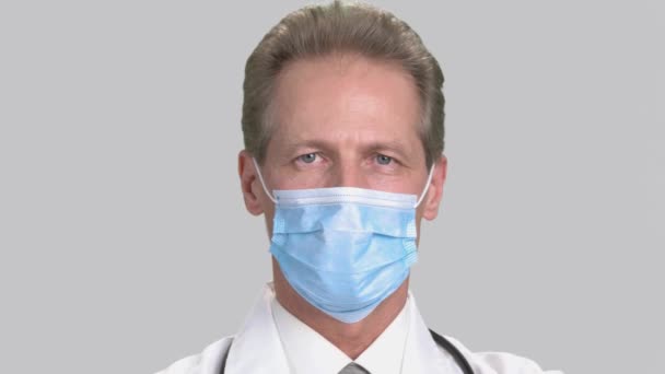 Close-up retrato de homem grave médico em máscara cirúrgica branca . — Vídeo de Stock