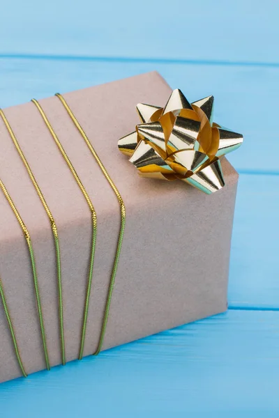 Złote pole wstążki i prezent owinięty w papier pakowy. — Zdjęcie stockowe