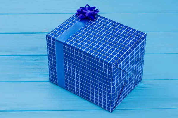 Caja regalo azul con lazo y madera azul . —  Fotos de Stock