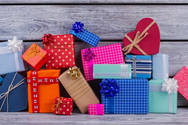 Pile of colorful gift boxes on wooden background.
