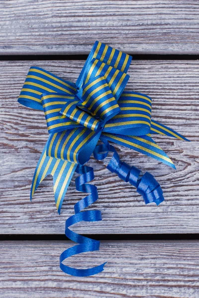 Blue gift bow on wooden background.