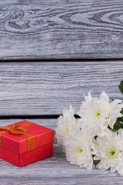 Fresh flowers and present box on wooden background.