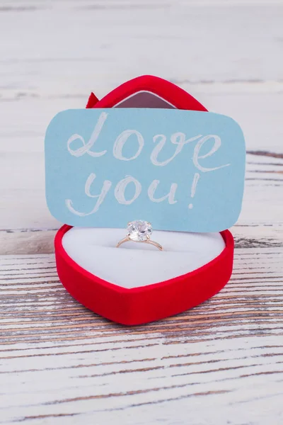 Engagement ring in box and love message.