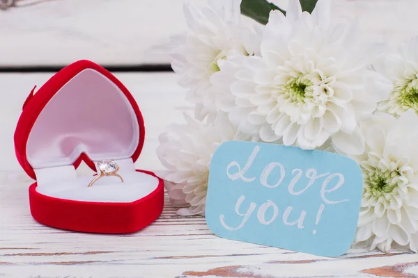 Diamond ring in box and bouquet of flowers.