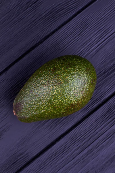 Grüne Avocado auf dunklem Holz, Draufsicht. — Stockfoto