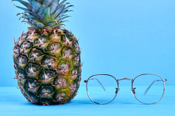 Pineapple and eyeglasses on blue background.