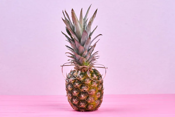 Pineapple in eyeglasses on pink background.