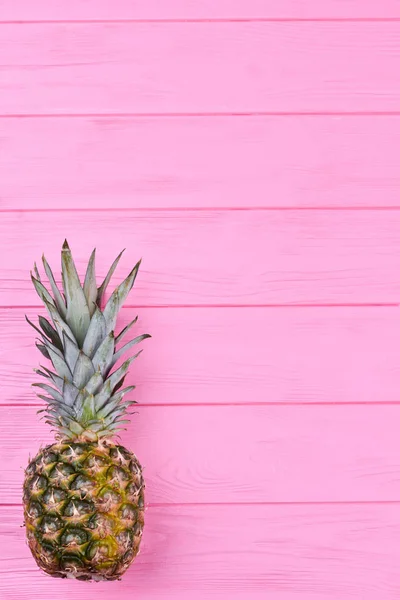 Juicy pineapple on pink wooden background.