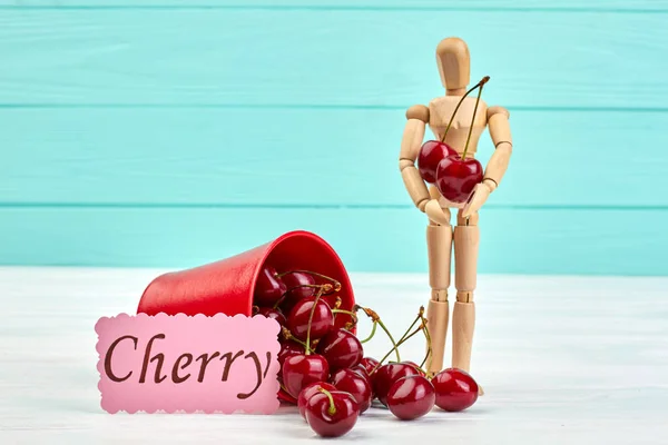 木製の人形と赤い甘いチェリー. — ストック写真