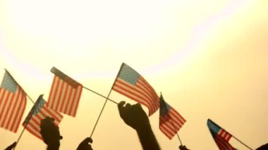 İnsanların elinde Amerikan bayrakları kapatın. Vatansever insanlar ABD bayrakları akşam gökyüzüne kaldırdı. Ülkenin bağımsızlık kavramı.