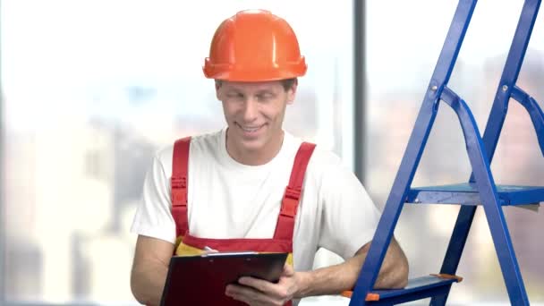 Constructor sonriente escribiendo en portapapeles . — Vídeo de stock