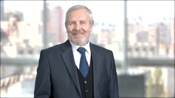 Smiling older businessman, blurred background. — Stock Video