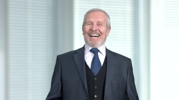 Elderly businessman laughing on blurred background. — Stock Video