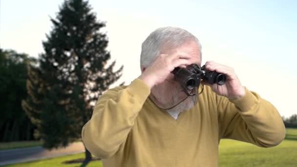 Εσωτερικη ηλικιωμένος άνδρας κοιτάζοντας μέσα από κιάλια. — Αρχείο Βίντεο