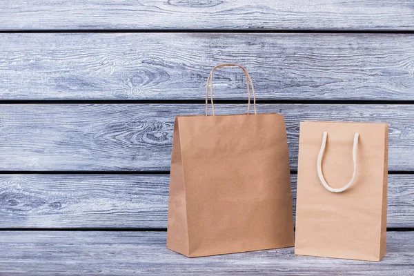 Brown paper shopping bags on wooden background.