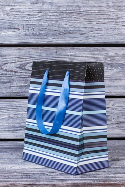 Синий пакет для подарка на деревянном фоне . — стоковое фото