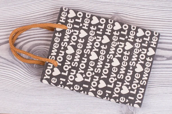 Black gift bag with white hearts pattern.