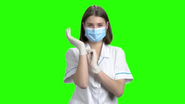 Portré, fiatal női orvos fektetni kesztyű. — Stock videók