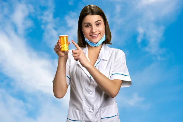 Pretty female doctor pointing on pills. — Stock Photo, Image