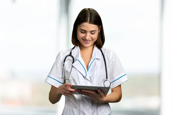 Pretty smiling doctor using digital tablet.