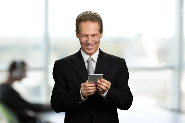 Empresário feliz olhando para seu smartphone . — Fotografia de Stock