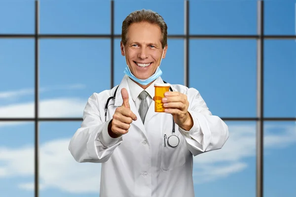 Happy doctor with pills on sky background. — Stock Photo, Image