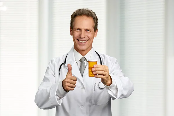 Happy professional doctor holding pills.