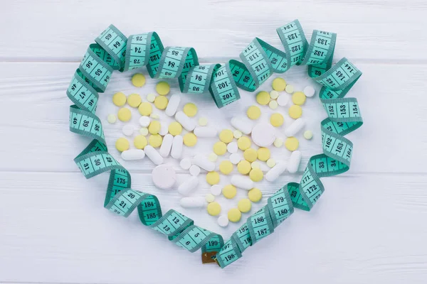 Heart-shaped measuring tape and pills.
