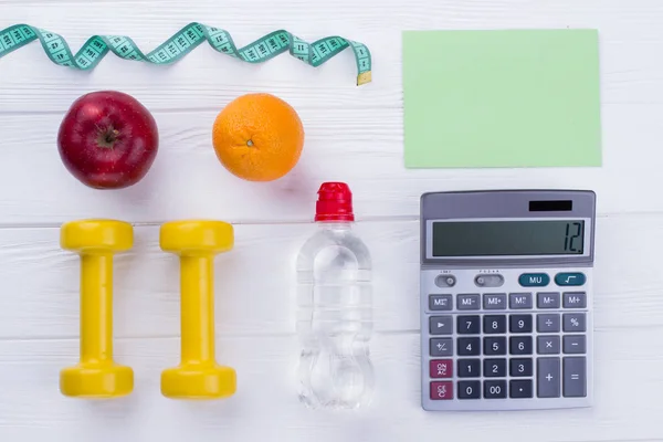 Fitness equipment, fruits, calculator and paper card.