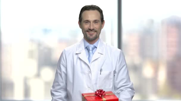 Smiling male pharmacist holding gift box. — Stock Video