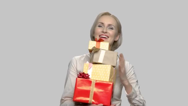 Gelukkig vrouw met gift dozen op grijze achtergrond. — Stockvideo