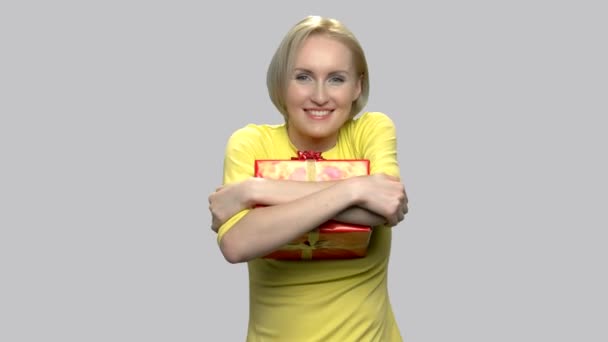 Frau umarmt Geschenkbox auf grauem Hintergrund. — Stockvideo