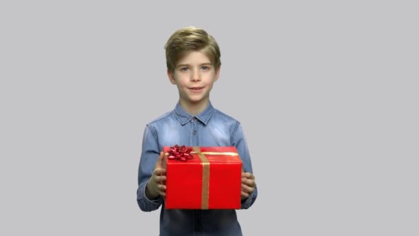 Pequeño niño dando caja de regalo sobre fondo gris . — Vídeos de Stock