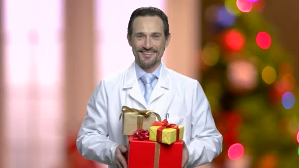 Sonriente médico dando regalos en Christrmas fondo . — Vídeos de Stock