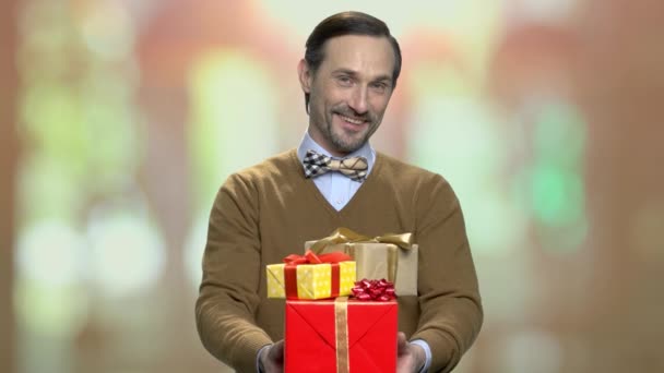 Mann mit Geschenkschachteln blickt in Kamera. — Stockvideo