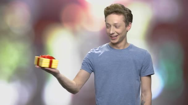 Teenager Junge hält Geschenkbox mit Schleife. — Stockvideo