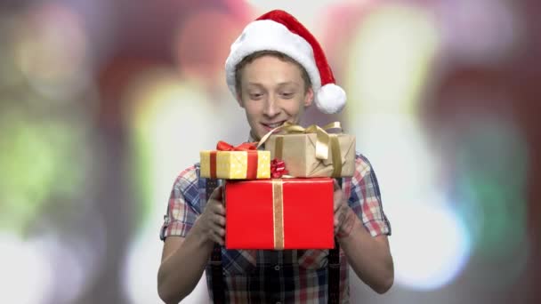 Cheerful guy in Christmas hat giving present boxes. — Stock Video