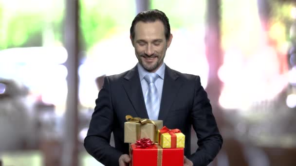 Souriant homme d'affaires attrayant tenant des boîtes-cadeaux . — Video