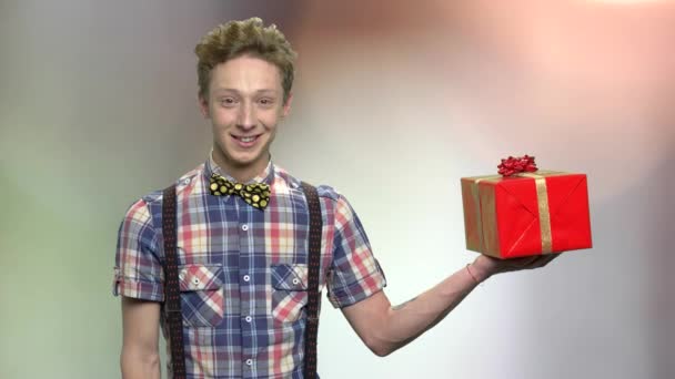 Elegante Teenager-Junge präsentiert Geschenkbox. — Stockvideo