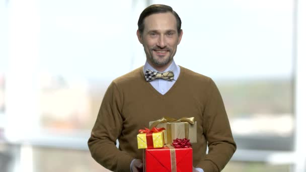 Elegante man met geschenkdozen op onscherpe achtergrond. — Stockvideo