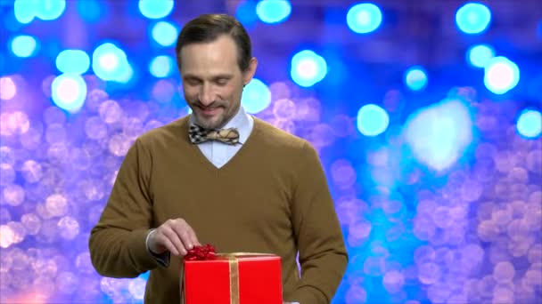 Mann mit Geschenkbox auf blauem Bokeh-Hintergrund. — Stockvideo